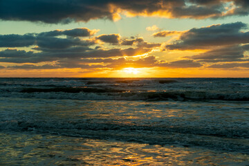 Obraz premium Evening landscape of sea water waves crushing on sandy beach at sunset