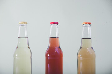 Three vibrant liquid-filled bottles set against a serene light green background.