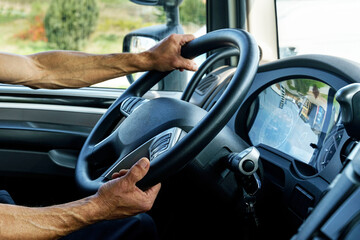 Close up of truck driver behind the steering wheel in a cabin