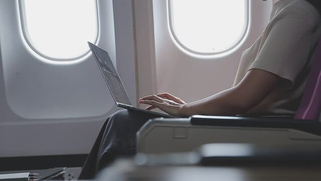 .Woman using laptop while is sitting in plane near window.