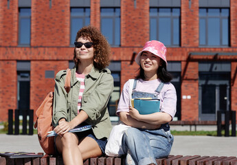 Waist up portrait of two smiling girls enjoying sunlight outdoors on college campus, copy space