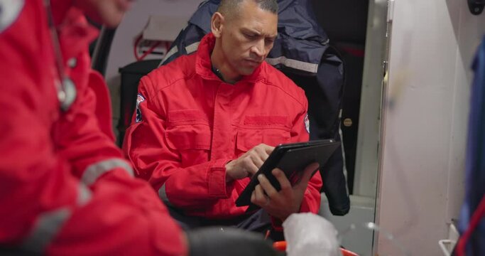 Talking, man and a tablet for ambulance emergency, communication and training. Teamwork, digital and a medical employee working on the web with technology for service, analysis or research for rescue