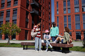 Wide angle view at diverse group of students studying together outdoors in urban setting at modern college campus, copy space
