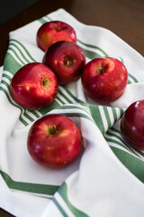 Many red apples spilling onto striped kitchen towel bright fresh clean