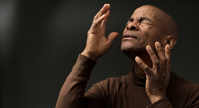 black man praying to god with hands together on grey background with people stock image stock photo