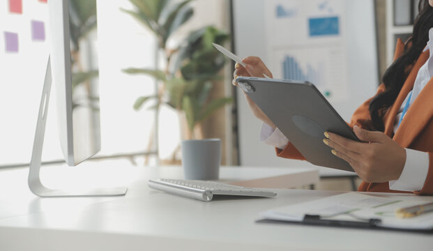 Close up Business woman using calculator and laptop for do math finance on wooden desk, tax, accounting, statistics and analytical research concept