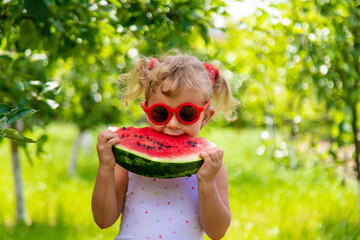 A child eats a watermelon in the park. Selective focus.