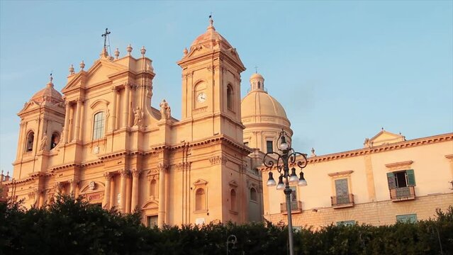 noto sicily italy cathedral wide shot with trees bushes light post in front and sky above