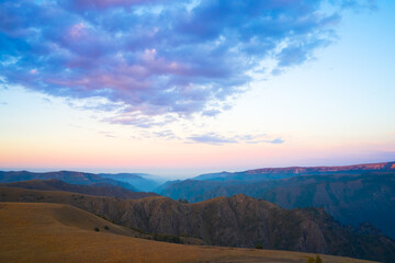 Picturesque panoramic view of the mountain rocky terrain at sunset. Fog in the gorge. Shooting from a drone.