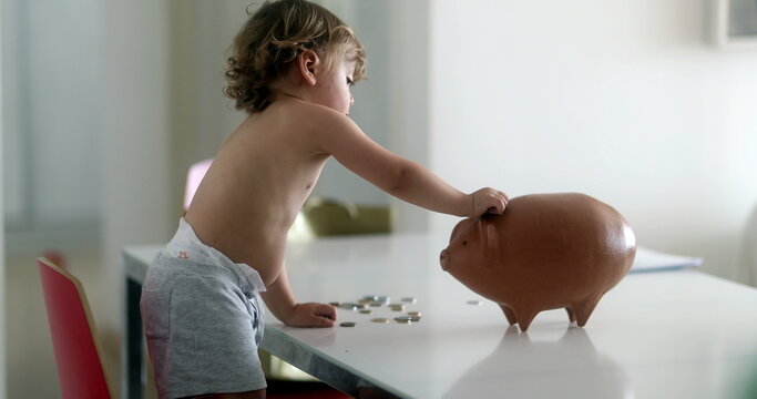 Adorable baby boy adding savings inside piggy bank