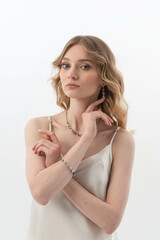 Close up portrait of a beautiful elegant woman with stylish jewelry on a white gray background. Girl in white shirt