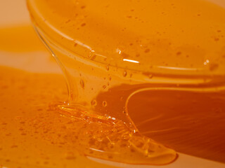 Liquid shower gel flows gracefully across a bright orange background. The translucent waves of the...