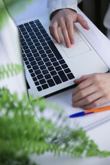 Online shopping concept. There is a white laptop on a white table. next to it is a notepad for notes and a worker’s hands on a keyboard and smartphone