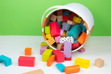 Children's toy, wooden constructor, poured out of a bucket on a lime color background. Kids toys. - obrazy, fototapety, plakaty