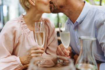 Close up of beautiful couple in a restaurant, on romantic date. Wife and husband kissing, having romantic moment at restaurant patio.