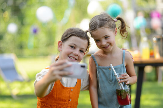 Cousins taking selfie at family garden party. Family reunion at a garden barbecue party.