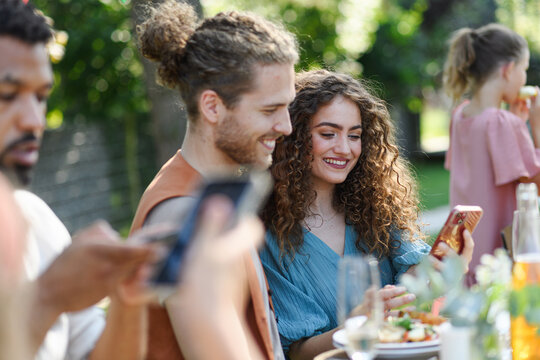 Portrait of couple sitting at the table with family and friends at the family garden party.