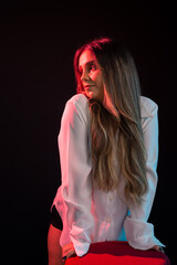 Fototapeta premium Beautiful young Caucasian woman wearing white clothing standing next to a red stool.