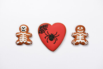 The hand-made eatable gingerbread heart with spider and sceletons on white background - 660123693