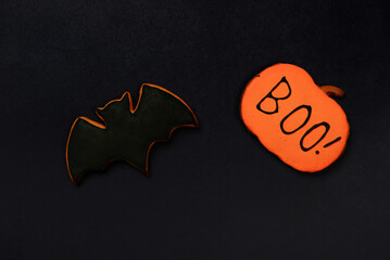 The hand-made eatable gingerbread Halloween  bat and pumpkin with boo inscription on black background - 660123696