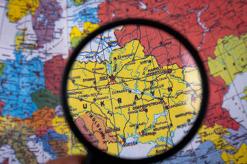 Zoom in on map of Ukraine with magnifying glass. Black magnifying glass under colorful world map, close-up