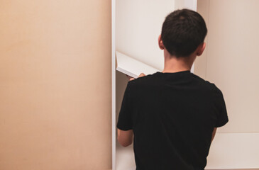 A young man sets up a shelf inside in the wardrobe.