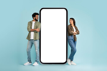 Multiracial man and woman standing by big phone with mockup