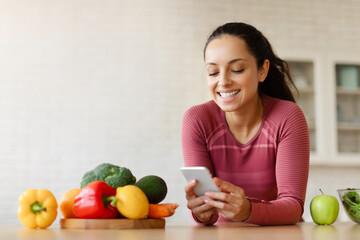 Fototapeta premium Fit Lady Using Weight Loss Application On Cellphone In Kitchen
