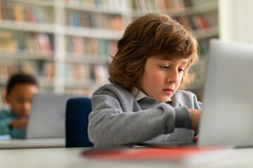 School kids at desks using laptops in the classroom