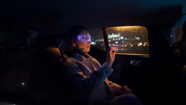 Portrait of an intelligent young woman sitting in the back of a car wearing virtual reality glasses