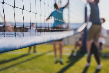 Volleyball game, junior teenage school team of kids play volleyball, players on the outdoor playground with net and green lawn grass court, sports children team during the game, summer sunny - obrazy, fototapety, plakaty