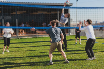 Volleyball game, junior teenage school team of kids play volleyball, players on the outdoor playground with net and green lawn grass court, sports children team during the game, summer sunny