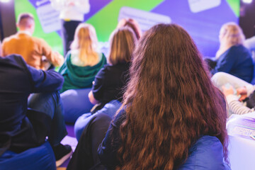 Audience at the conference hall listen to lecturer, people listen to speaker on a bean bags stage at master-class, college students in the auditorium, participants of corporate business seminar