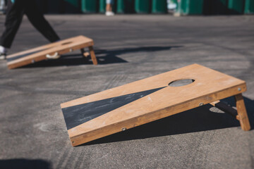 Cornhole game set, process of throwing bean bags, kids children tossing bean sacks, corn hole  in the backyard, wooden boards for corn-hole tournament in the summer sunny day