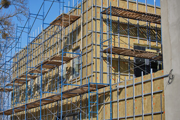 thermal insulation of a building at the moment of construction with installed scaffolding