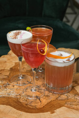 Four bright alcoholic cocktails in glasses on wooden cafeteria table