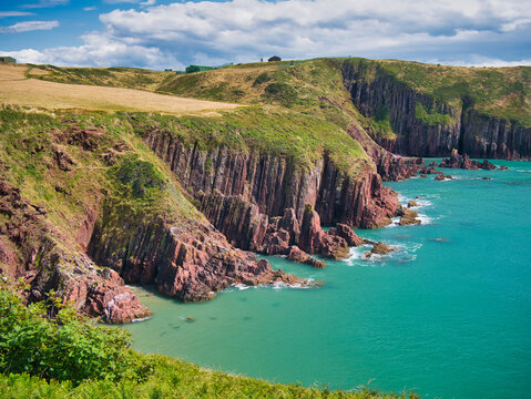 Coastal red cliffs near Manorbier in Pembrokeshire, Wales, UK - the vertically inclined rock strata of the bedrock is of the Milford Haven Group - Argillaceous rocks and sandstone, interbedded.