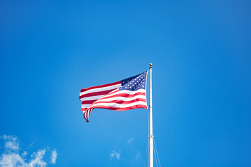 Mast with the flag of the United States of America against the blue sky.