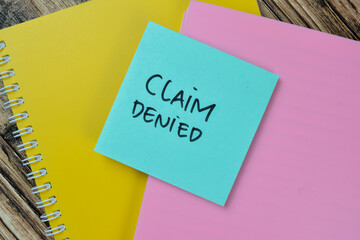 Concept of Claim Denied write on sticky notes isolated on Wooden Table.
