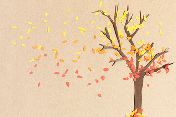 A bare cardboard tree with loose leaves. Red, orange, and yellow tree leaves flying. Fall landscape.