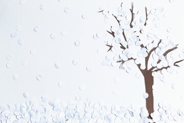 A handmade cardboard bare tree covered in snow on a white background. Winter landscape. Snow storm.