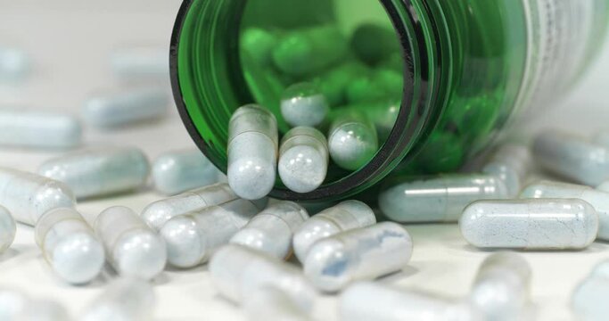 Capsules with blue powder and open green container lies on the white table. In reality these are tablets of copper in chelated form. Cinema 4K 60fps tilt video