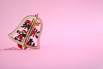 Wooden Christmas bell decoration on pink background