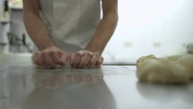 Close-up view of baker shaping dough pieces into bread rolls_2