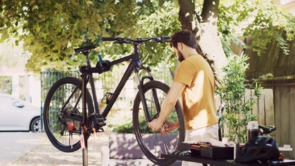 Determined male cyclist carefully removing damaged bicycle tire for replacing with new. Young...