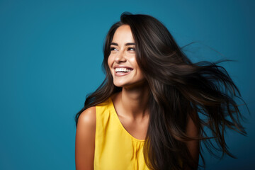 portrait of smiling young woman laughing against blue background