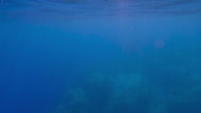 POV underwater shot, man swimming under surface of blue water of Mediterranean sea