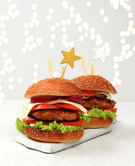 Two Christmas burgers with tomatoes, olives, cream cheese, onions, cutlets on a holiday table with...