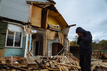 Sad man on ruined house. Hopeless, homelessness, result of military conflicts and natural disasters...