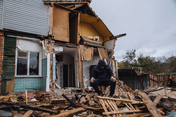 Sad man on ruined house. Hopeless, homelessness, result of military conflicts and natural disasters...